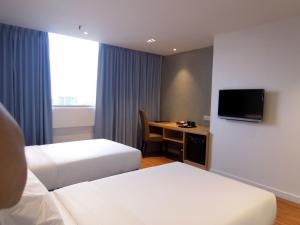 a hotel room with two beds and a desk at Hotel Excelsior Ipoh in Ipoh