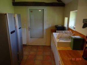 a kitchen with a white refrigerator and a door at Ferme rénovée avec verger, 7 km du Mans, cheminée, 4 chambres, draps inclus, calme assuré - FR-1-410-251 in La Bazoge