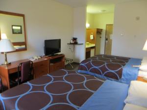 a hotel room with a bed and a desk and a television at Super 8 by Wyndham Edmonton/West in Edmonton