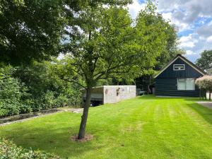 a tree in a yard in front of a house at A cosy house close to Giethoorn and the Weerribben Wieden National Park with a boat available hire in Giethoorn