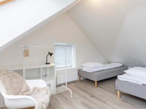 a attic room with two beds and a chair at Holiday home Hals CXXI in Hals