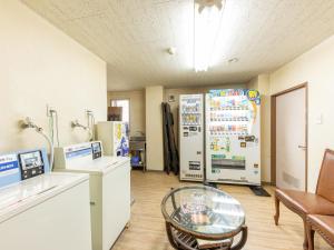Zimmer mit einem Kühlschrank und einem Glastisch. in der Unterkunft Tabist Ryosou Minatosou Joetsu in Naoetsu