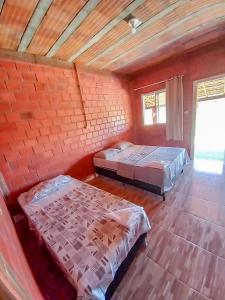 two beds in a room with a brick wall at Pousada do Mané in Santo Amaro