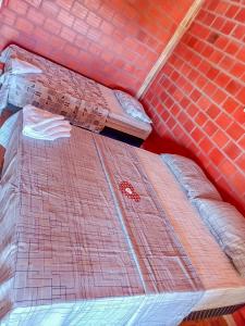 a bed in a room with a brick wall at Pousada do Mané in Santo Amaro