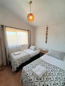 a bedroom with two beds and a window and a chandelier at Eco Parcela La Chacra in Catapilco