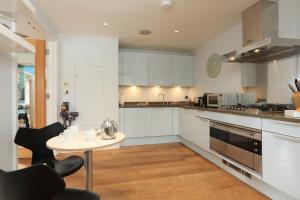 a kitchen with white cabinets and a table and chairs at 9 Dart Marina in Dartmouth