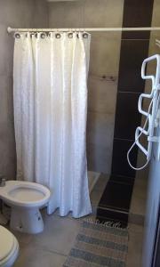 ein Badezimmer mit einem weißen Duschvorhang und einem WC in der Unterkunft Las Macluras Suite in Tandil