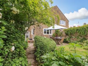 a garden with a table and an umbrella at Pippins Loders in Bridport