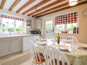 a kitchen with a table and chairs and a kitchen with windows at Pippins Loders in Bridport