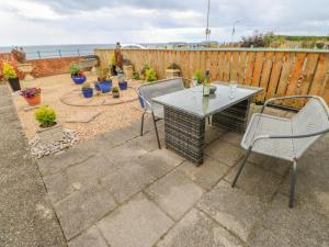 a patio with a table and chairs and the ocean at Beach Cove View in Newbiggin-by-the-Sea
