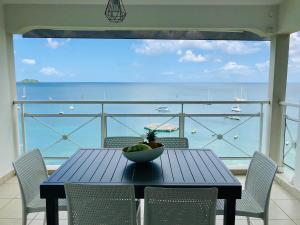 einen Tisch mit Stühlen und eine Obstschale auf dem Balkon in der Unterkunft Appartements T3 standing Vue mer époustouflante à quelques pas de la plage in Les Trois-Îlets