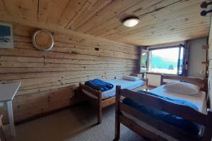 two beds in a room with a wooden wall at Chalet at the foot of the Nordic domain in La Clusaz