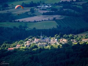 Ein Paraglider fliegt über eine Kleinstadt auf einem Hügel in der Unterkunft Gîte indépendant avec terrasse et garage à La Chabanne - FR-1-489-187 in La Chabanne