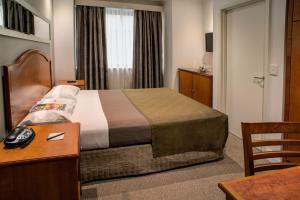a hotel room with a bed and a desk with a telephone at Great Southern Hotel Sydney in Sydney