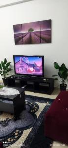 sala de estar con TV de pantalla plana en la pared en D'Zara Homestay, en Sepang