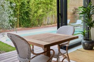 - une table en bois et 2 chaises sur une terrasse couverte dans l'établissement Les pénates bordelaises - Maison d'hôtes - Guesthouse, à Bordeaux