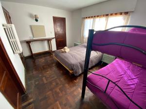 um quarto com um beliche com lençóis roxos em Hostel Planeta Cumbrecita em La Cumbrecita