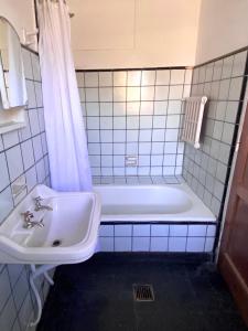 a white bathroom with a tub and a sink at Hostel Planeta Cumbrecita in La Cumbrecita