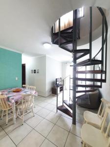 a living room with a table and a spiral staircase at Cobertura duplex- 50m da Praia Grande- Ubatuba in Ubatuba