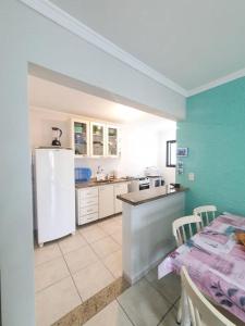 a kitchen with a white refrigerator and a table with chairs at Cobertura duplex- 50m da Praia Grande- Ubatuba in Ubatuba