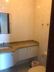 a bathroom with a sink and a toilet and a mirror at Cobertura duplex- 50m da Praia Grande- Ubatuba in Ubatuba