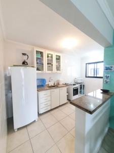 a kitchen with a white refrigerator and white cabinets at Cobertura duplex- 50m da Praia Grande- Ubatuba in Ubatuba