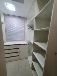 a walk in closet with white shelves and a window at Casa 3quartos rota Maragogi Carneiros in São José da Coroa Grande