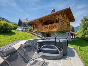 dom z wanną z hydromasażem i krzesłami przed nim w obiekcie Chalet paisible à Morillon avec jacuzzi et proche des pistes skiables - FR-1-642-66 w mieście Morillon