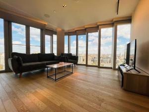 salon z kanapą, telewizorem i oknami w obiekcie Manhattan Loft Gardens, Stratford E20 w Londynie