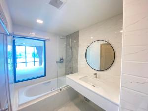 ein Badezimmer mit einer Badewanne, einem Waschbecken und einem Spiegel in der Unterkunft Mayuu Ayutthaya Hotel in Ban Ko Rian