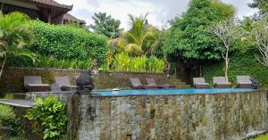 a stone wall with chairs and a swimming pool at Giri Carik in Sidemen