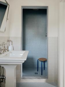 a bathroom with a sink and a stool in the shower at The James Bradley in Bradley Beach