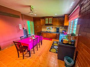 a dining room with a pink table and a kitchen at Nail Guest House Kuala Besut in Kampong Nail