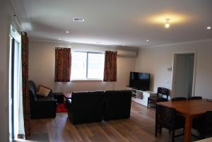Una sala de estar con un sofá, una mesa y un televisor. en Time to Relax, en Portarlington