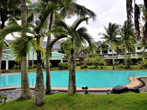 a swimming pool with palm trees in front of a building at Chateau Bleu Resort in Calamba
