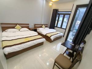 sypialnia z 2 łóżkami, stołem i oknem w obiekcie Nhà Nghỉ QUANG TRUNG w mieście Dồng Văn