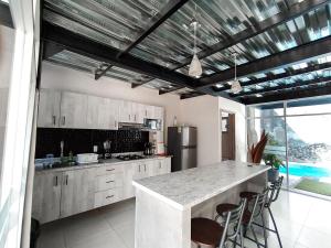 een keuken met witte kasten en een aanrecht met krukken bij Casa con alberca dentro de ex-hacienda en Atlixco in Atlixco