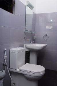 a bathroom with a white toilet and a sink at Traveller's Home Hotel in Tissamaharama