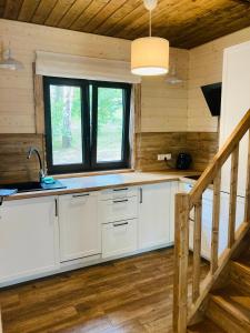 a kitchen with white cabinets and a window in a cabin at Modrynowe Domki in Wetlina