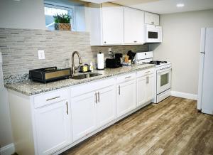 a kitchen with white cabinets and a sink and a refrigerator at Cozy and Modern 1BR Apartment with WiFi and Dogs Welcome in Baltimore