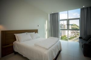 a bedroom with a white bed and a large window at Sky Hotel in Shkodër