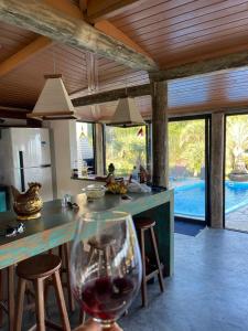 uma cozinha com um balcão com um copo de vinho em Villa Santorini Praia do Rosa com piscina e jacuzzi em Praia do Rosa