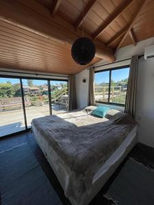 ein Schlafzimmer mit einem großen Bett in einem Zimmer mit Fenstern in der Unterkunft Villa Santorini Praia do Rosa com piscina e jacuzzi in Praia do Rosa