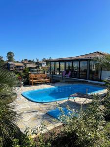 ein Swimmingpool vor einem Haus in der Unterkunft Villa Santorini Praia do Rosa com piscina e jacuzzi in Praia do Rosa