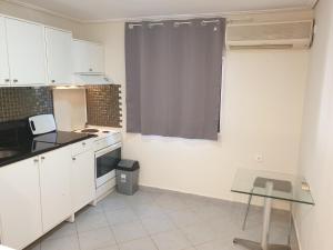 a kitchen with white cabinets and a table in it at Varkiza Cozy Seaside Apartment in Vari +2 photos