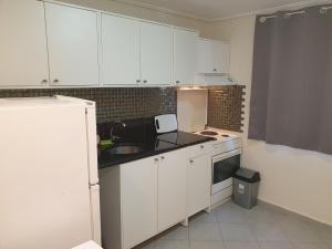 a kitchen with white cabinets and a sink and a microwave at Varkiza Cozy Seaside Apartment in Vari