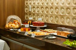 a buffet line with different types of cakes and pastries at CAMBRAIA HOTEL ARCOS in Arcos