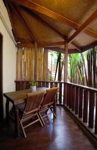 um deque de madeira com uma mesa e cadeiras num alpendre em Fisheye The Rooms - Family room em El Nido