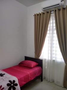 een slaapkamer met een bed en een raam met gordijnen bij FENDIONYA CORAL in Port Dickson
