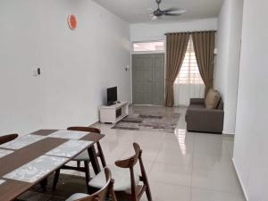 een woonkamer met een tafel en stoelen en een bank bij FENDIONYA CORAL in Port Dickson